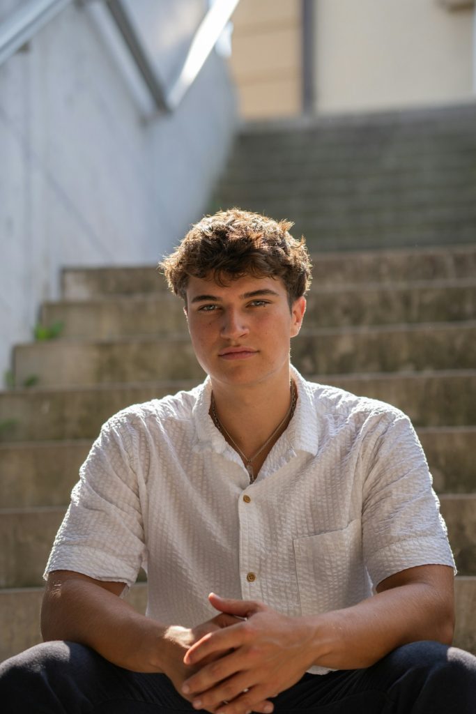 A young man sitting on the steps of a building